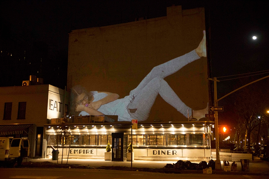 projection of a person napping projected above subway